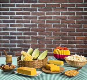 Various fruits in basket on table against brick wall