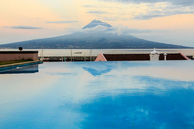  panoramic view of mountains reflected in swimming pool against blue sky