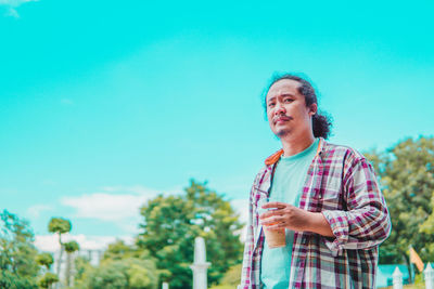 Portrait of young man standing against sky