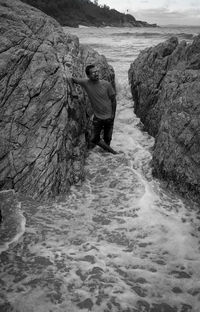 Rear view of man standing on rock at beach