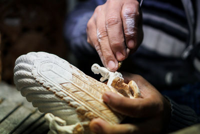 Close-up of man working on small religious sculpture 