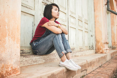 Thoughtful woman sitting outside house