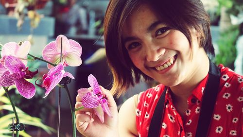 Close-up portrait of happy woman with pink flowers
