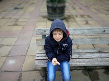 Boy having food while sitting on bench