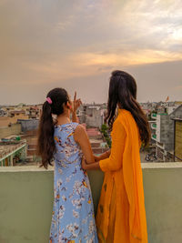 Rear view of woman looking at city against sky