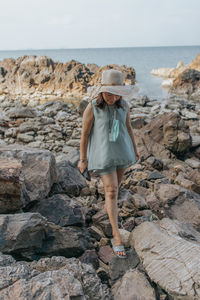 Beautiful woman walking on rock over sea