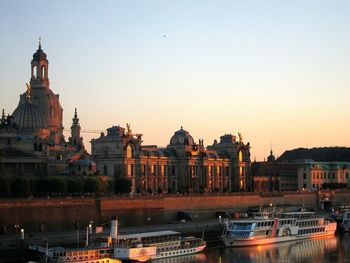 Boats in canal by dresden frauenkirche against sky during sunset