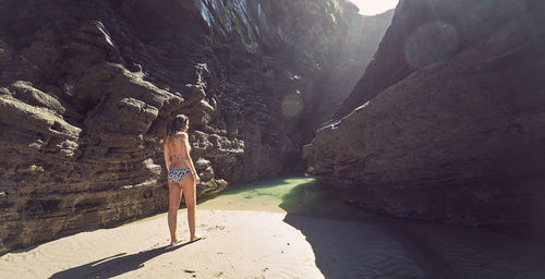 Woman standing on rock formation at beach