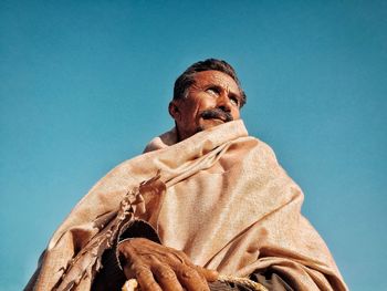 Low angle view of man looking away against clear blue sky