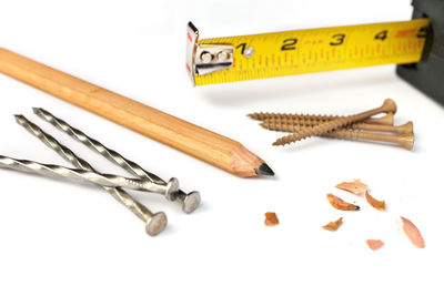 Carpenter's pencil with sharpening shavings, tape measure, framing nails and deck screws