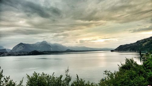 Scenic view of lake and mountains against cloudy sky