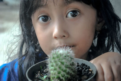 Close-up portrait of cute girl holding potted plant