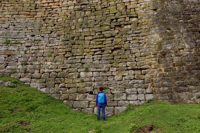 Rear view of man standing against stone wall