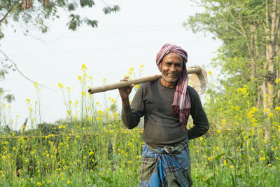 Portrait of smiling young man standing against plants