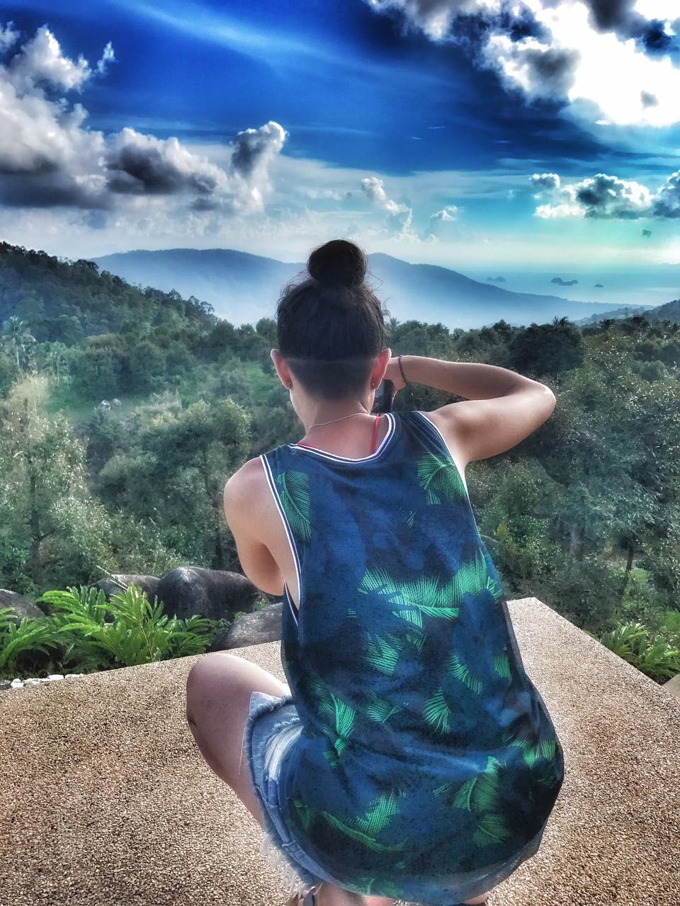 GIRL SITTING ON LANDSCAPE AGAINST SKY