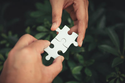 Cropped hands holding jigsaw piece outdoors