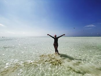 Rear view of man standing on beach against sky