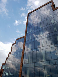 Low angle view of glass building against sky