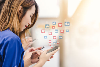 Digital composite image of young woman using mobile phone with heart and thumbs up signs