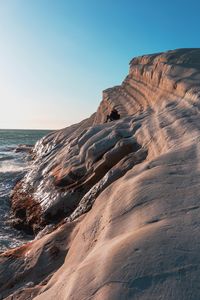 Rock formation on beach against clear sky