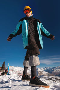 Smiling attractive man in a warm windbreaker, hat, standing and looking at the camera, against the