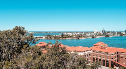 Cityscape by sea against clear blue sky