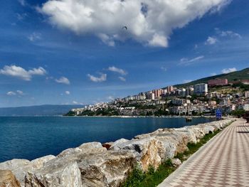 Sea by city against sky