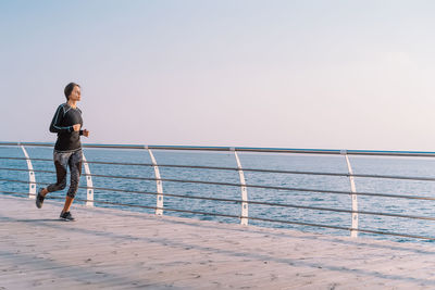 Full length of man standing on railing against sea