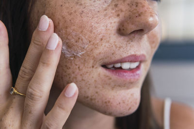 Hand of woman applying moisturizer on face