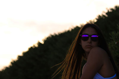 Portrait of woman wearing sunglasses against sky during sunset