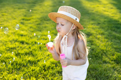 Portrait of young woman wearing hat standing against plants