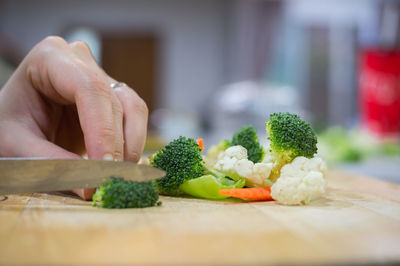 Cropped hand cutting vegetables on kitchen island