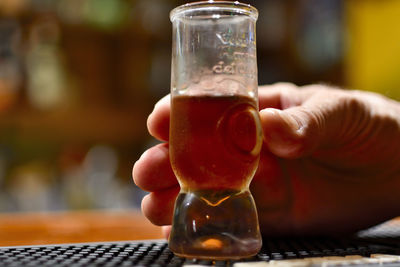Close-up of hand holding beer glass on table