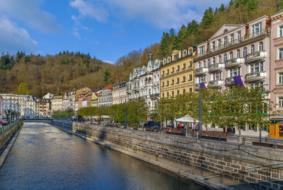 Bridge over river amidst buildings in city against sky