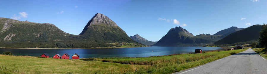 Rear view of people sitting on mountain against sky