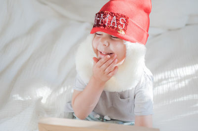 Toddler boy in santa claus costume with beard and red hat on white background