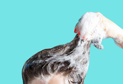 Close-up of hand holding ice cream against blue background