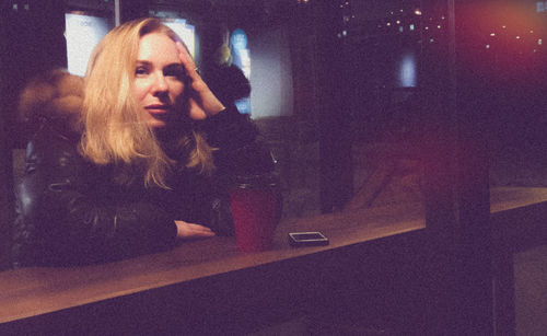 Woman looking at camera while sitting on table