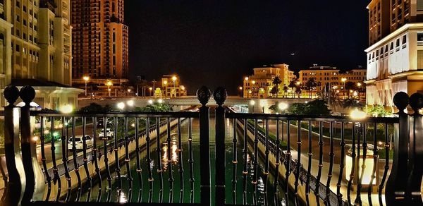 Bridge over canal against buildings in city at night