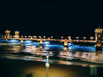 River by illuminated buildings against clear sky at night