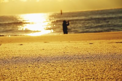 Silhouette man standing on beach against sky during sunset