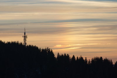 Silhouette trees and tower against sky during sunset