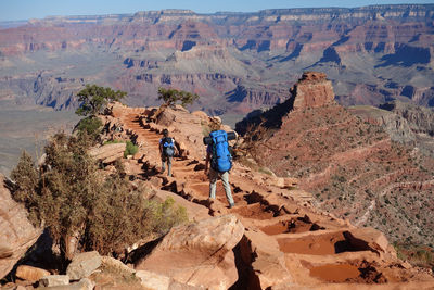 Rear view of people on rock against mountains