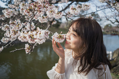 Young woman holding cherry blossoms in spring