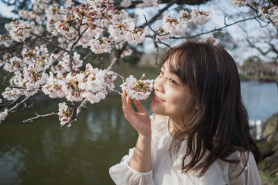 Portrait of young woman with cherry blossoms in spring