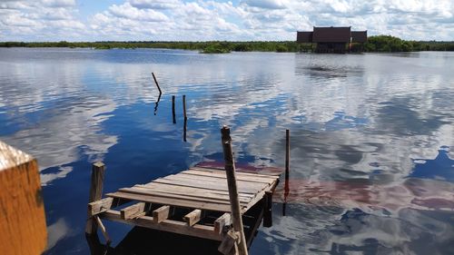 Wooden posts in lake against sky