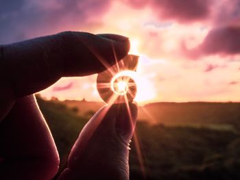 Midsection of person holding sun during sunset