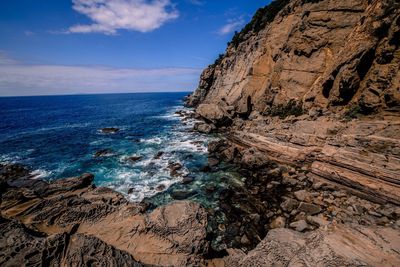 Rocky mountain by sea against sky