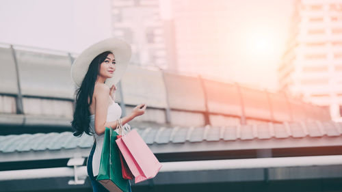 Woman with shopping bags standing in city