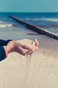 Midsection of person holding sand on beach